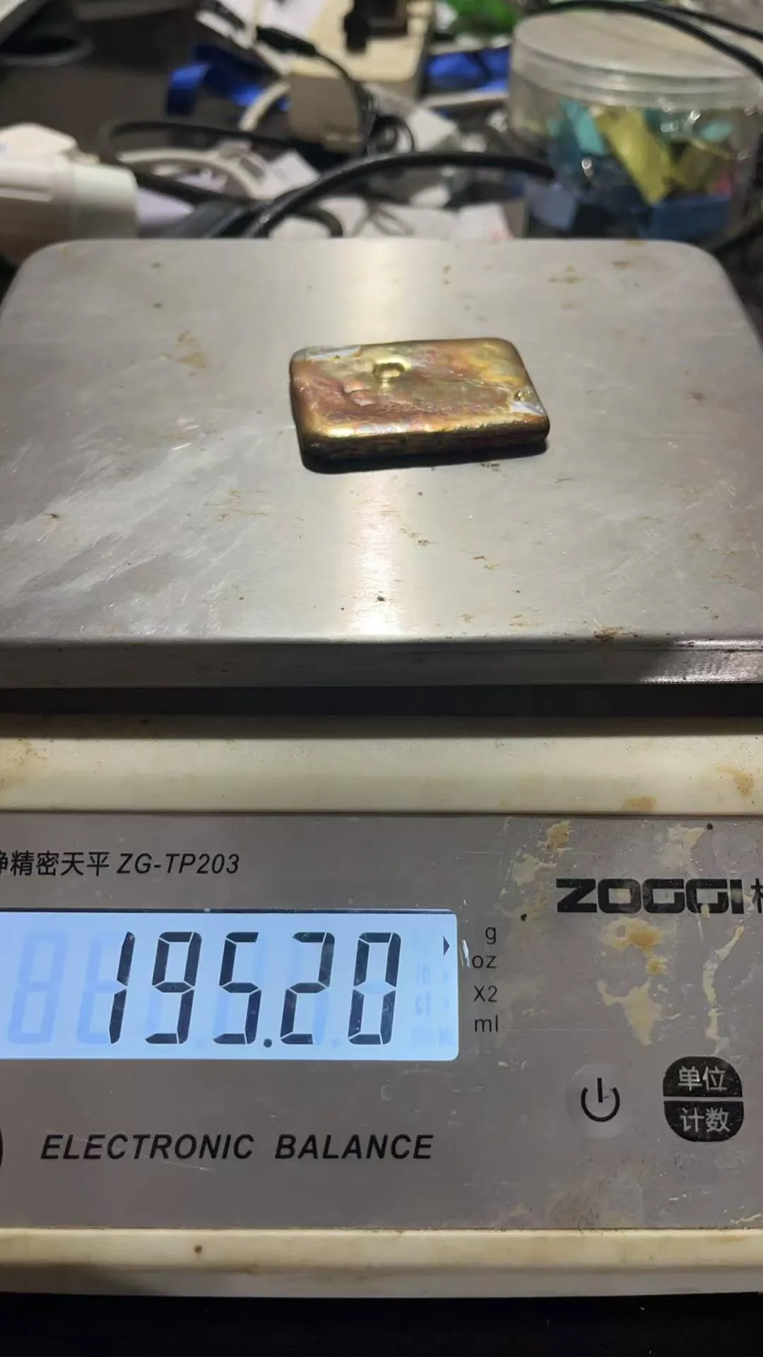 A flat gold doré plate on an electronic balance reading 195.20 grams