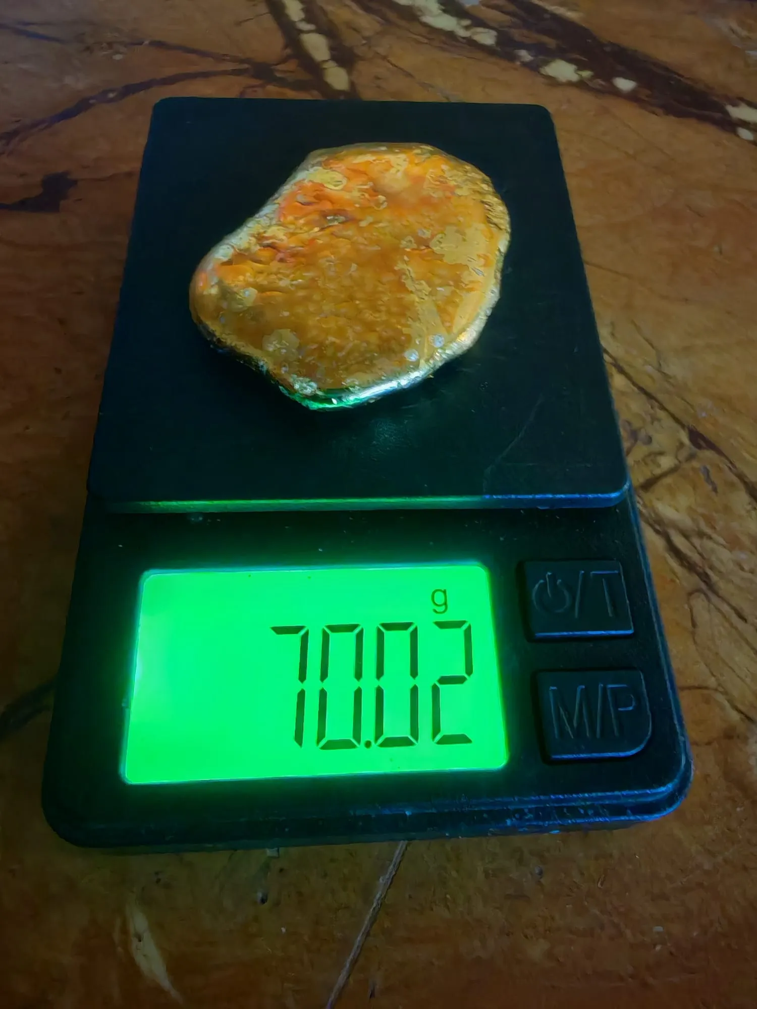 A textured gold nugget on a digital pocket scale reading 70.02 grams